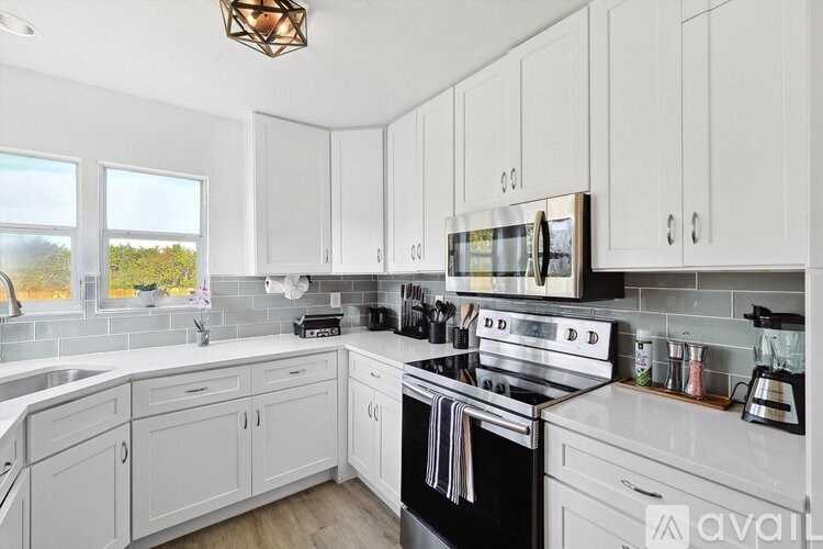 A kitchen with white cabinets and a black stove top oven.
