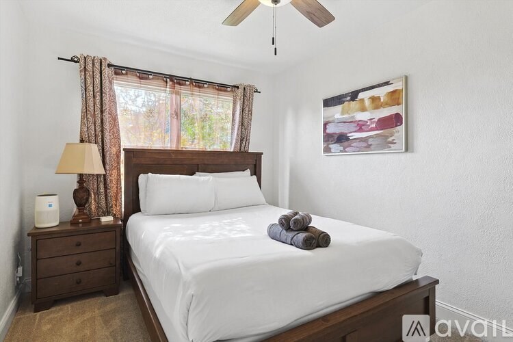 A bedroom with a bed, nightstand, and a ceiling fan.