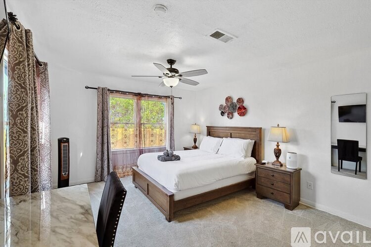 A bedroom with a large bed, a ceiling fan, and a chair.