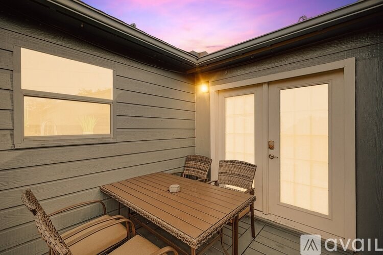 A wooden table and two chairs are on a porch.