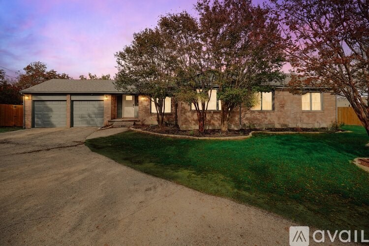 A house with a driveway and trees in front of it.