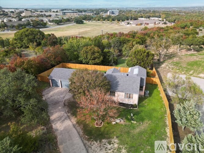 A bird's eye view of a house surrounded by a yellow fence and trees.