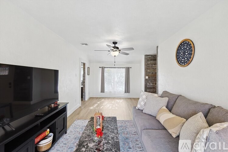 A living room with a grey couch and a black television.