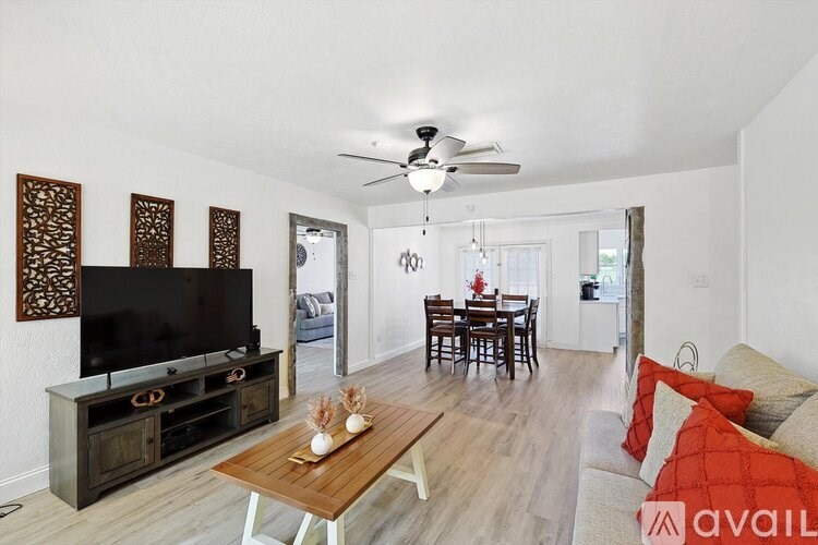 A living room with a television, a wooden coffee table, and a dining table with chairs.