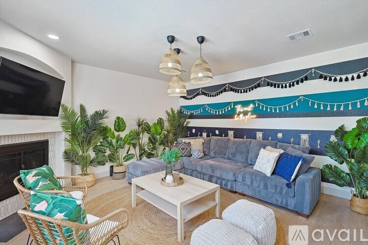 A living room with a grey couch, a fireplace, and a TV on the wall.