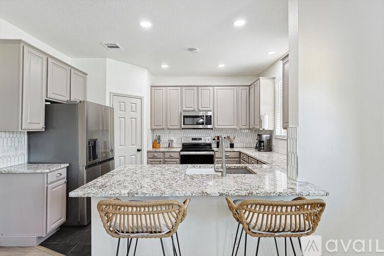 A kitchen with a marble countertop and two chairs.