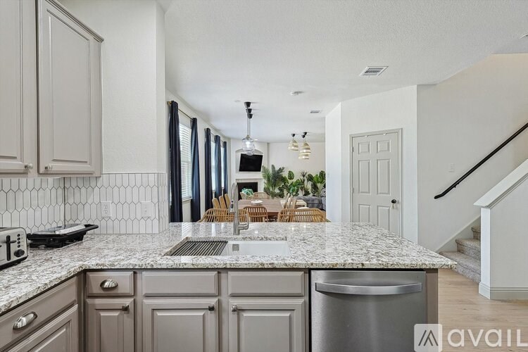 A kitchen with a marble countertop and a stainless steel dishwasher.