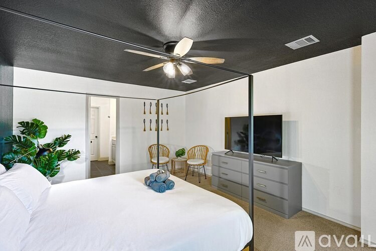 A bedroom with a bed, chair, and television.