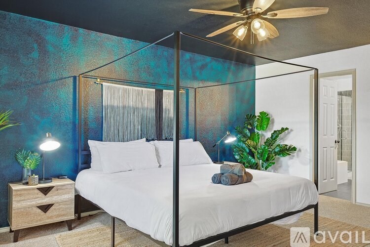 A bedroom with a four-poster bed and a ceiling fan.