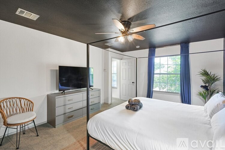 A bedroom with a bed, chair, and television.