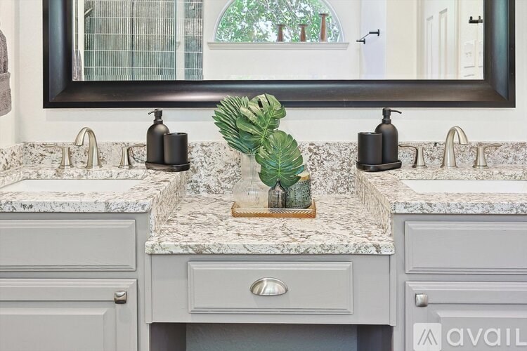 A bathroom with two sinks and a mirror above them.