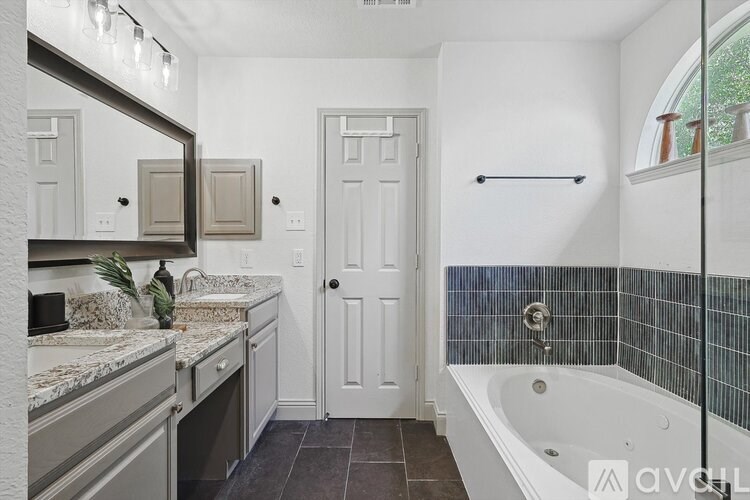 A bathroom with a white door and a black and white tiled wall.