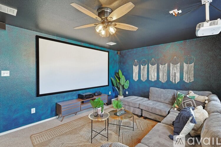 A living room with a grey couch and a white screen.
