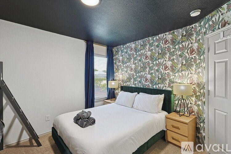 A bedroom with a floral wallpaper and a bed with white bedding.