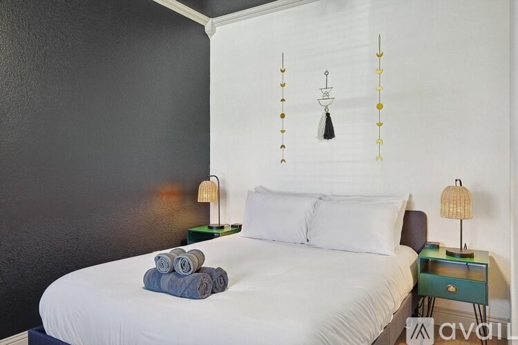 A bedroom with a white bed and a black wall.