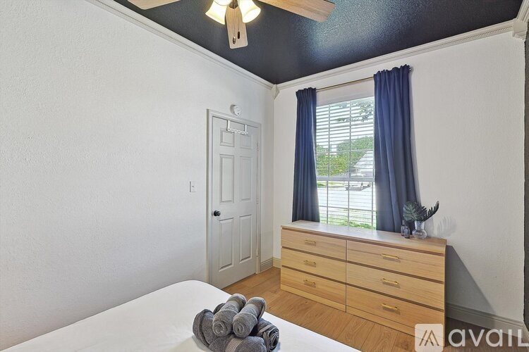 A bedroom with a bed, dresser, and window.