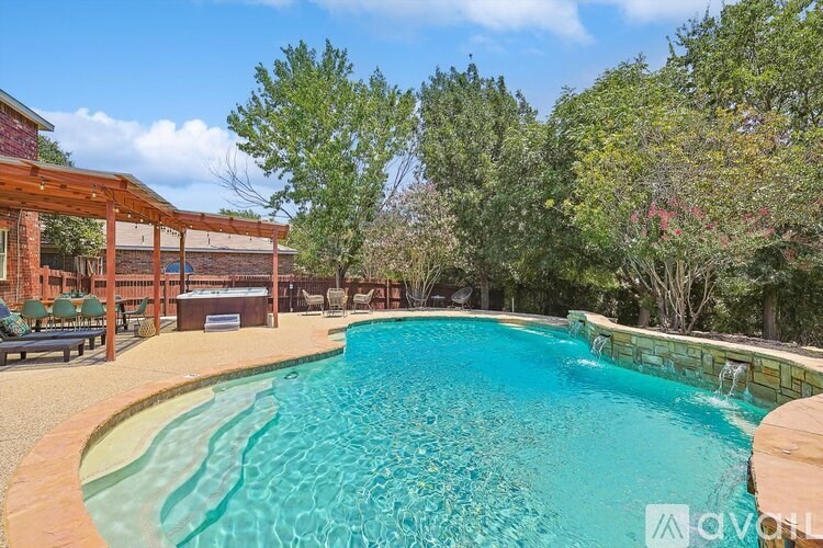A pool surrounded by trees and a wooden pergola.