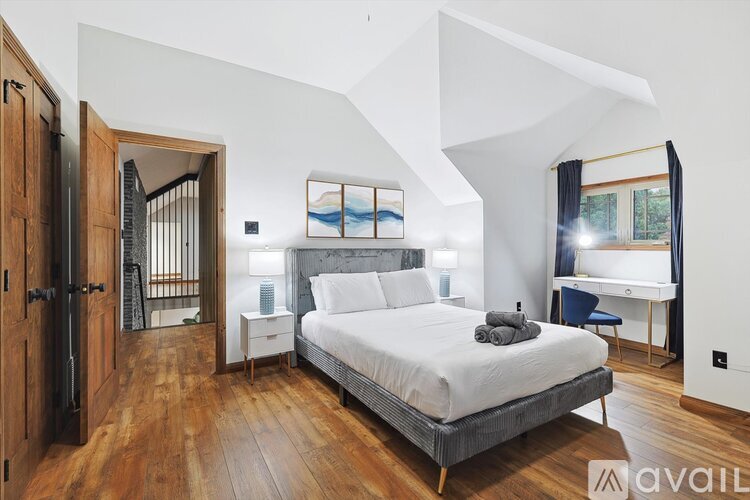 A bedroom with a large bed and a wooden floor.