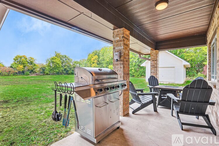 A BBQ grill is on a covered patio with chairs around it.