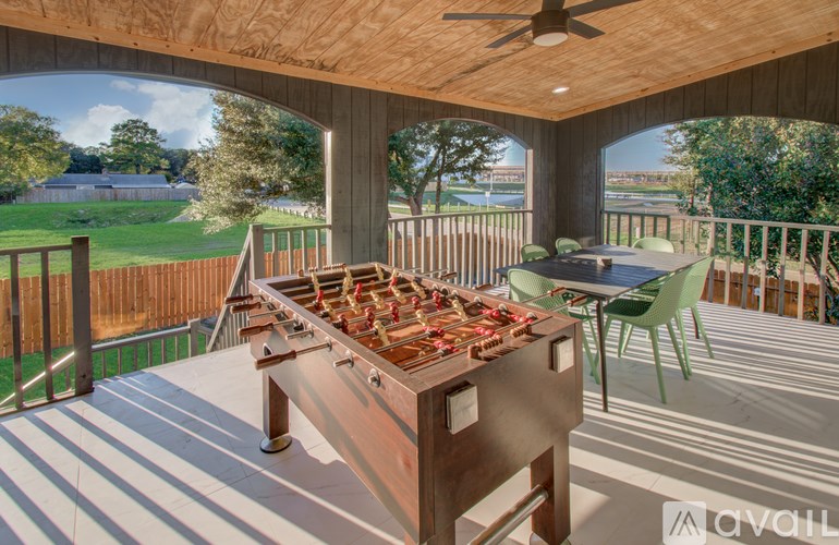 A foosball table is on a patio with a table and chairs.