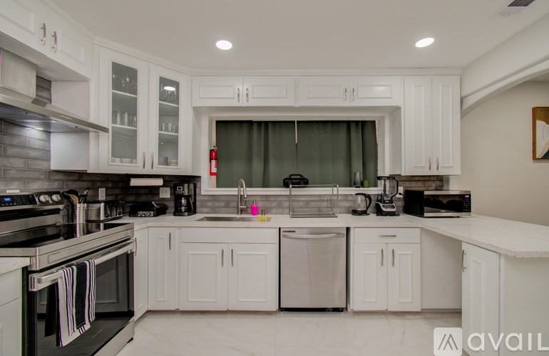 A modern kitchen with white cabinets and stainless steel appliances.