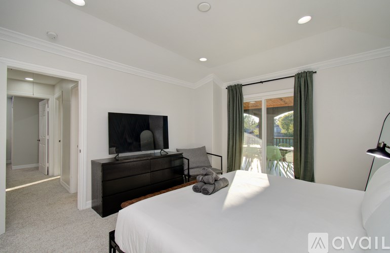 A bedroom with a large bed, a television, and a sliding glass door.