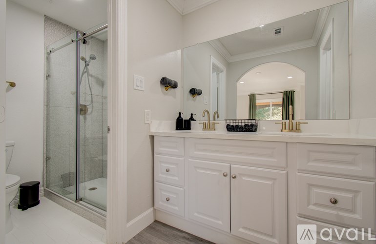 A bathroom with a white cabinet and a glass shower door.
