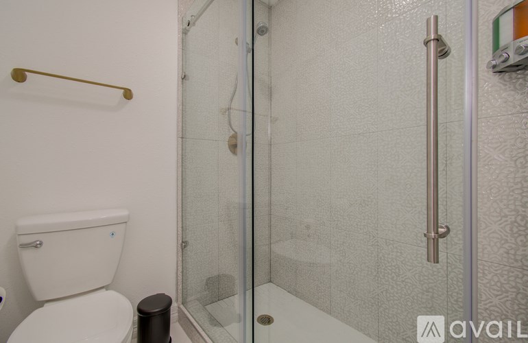 A white toilet with a gold bar and a glass shower door.