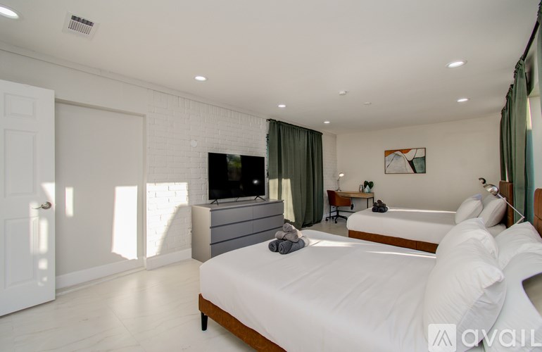 A bedroom with a large bed, a flat screen TV, and a window with curtains.