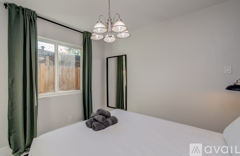 A bedroom with a white bed and green curtains.