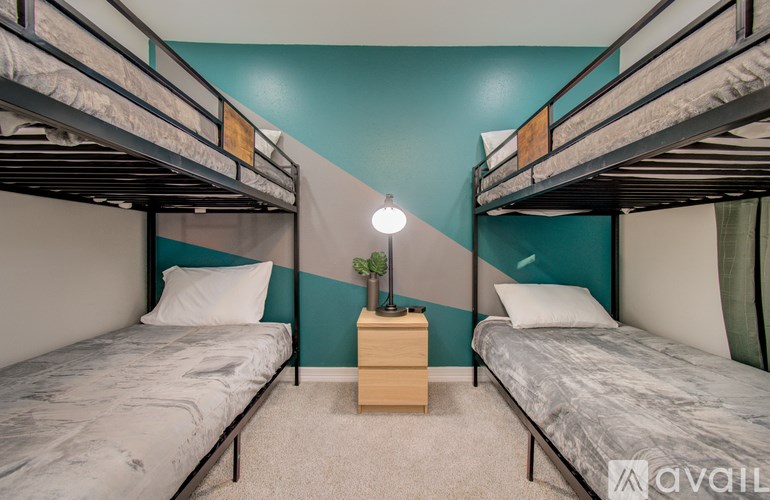 A room with two bunk beds and a nightstand with a lamp.