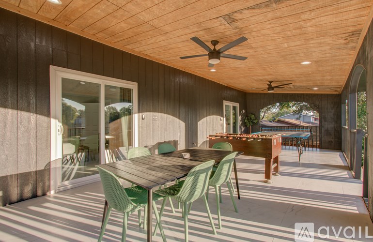 A wooden table with green chairs is on a patio.