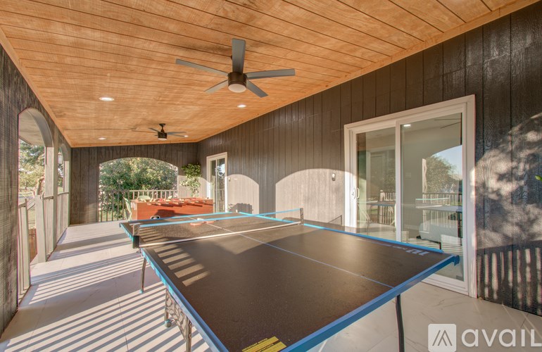 A ping pong table is in the middle of a room with a ceiling fan.