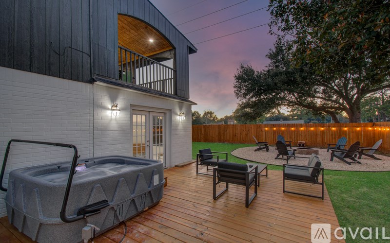A hot tub sits on a wooden deck in front of a house.