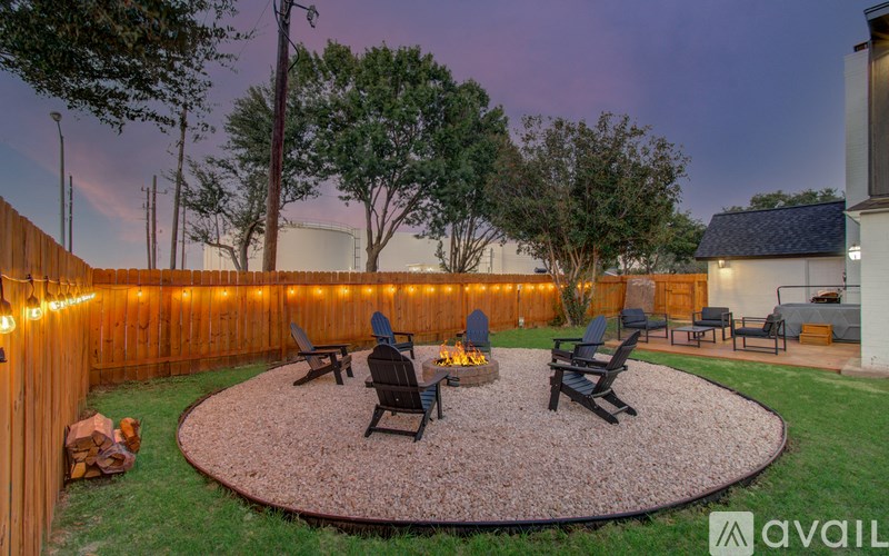 A backyard with a fire pit and chairs.