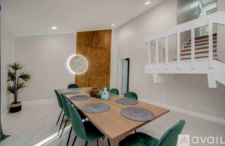 A dining room with a wooden table and green chairs.