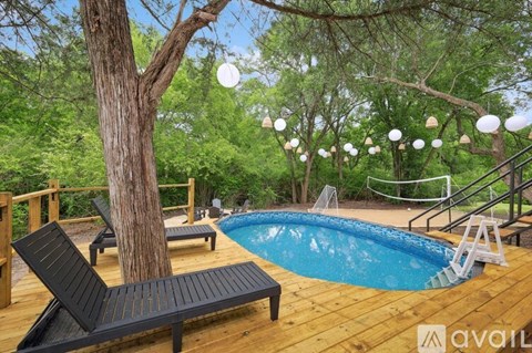 A pool surrounded by trees and deck chairs.