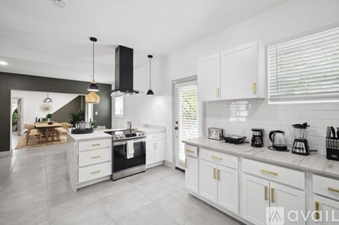 A modern kitchen with white cabinets and a marble countertop.