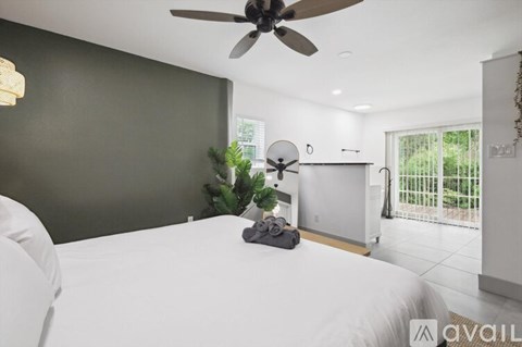 A bedroom with a white bed and a ceiling fan.