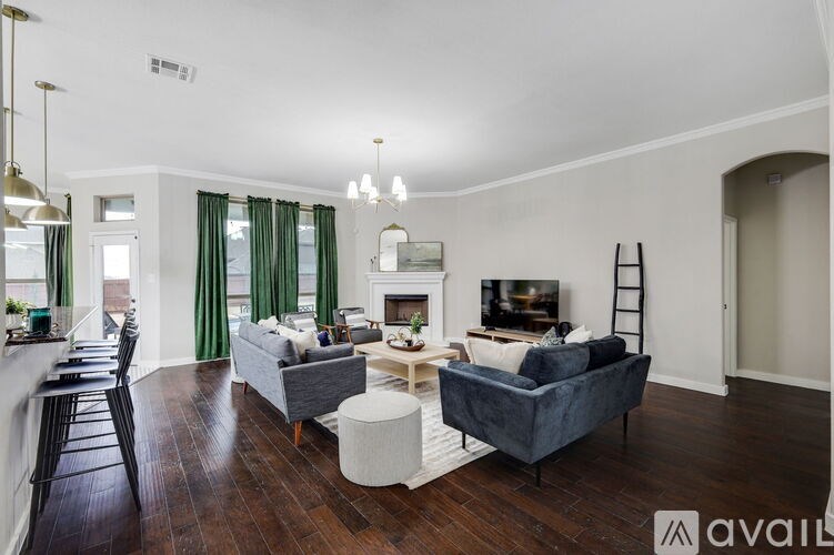 A living room with a grey couch, a white ottoman, and a black chair.