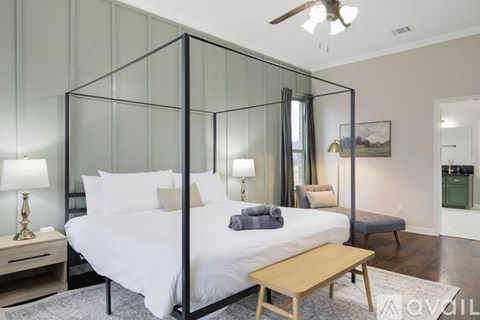 A bedroom with a four poster bed and a ceiling fan.