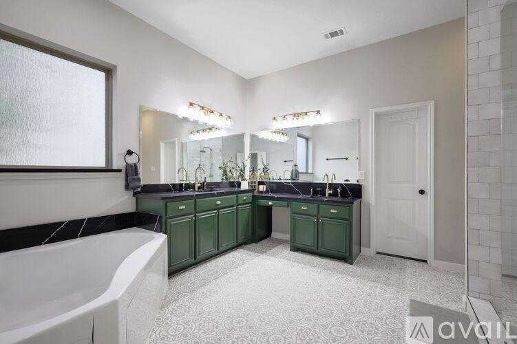 A bathroom with green cabinets and a white tub.