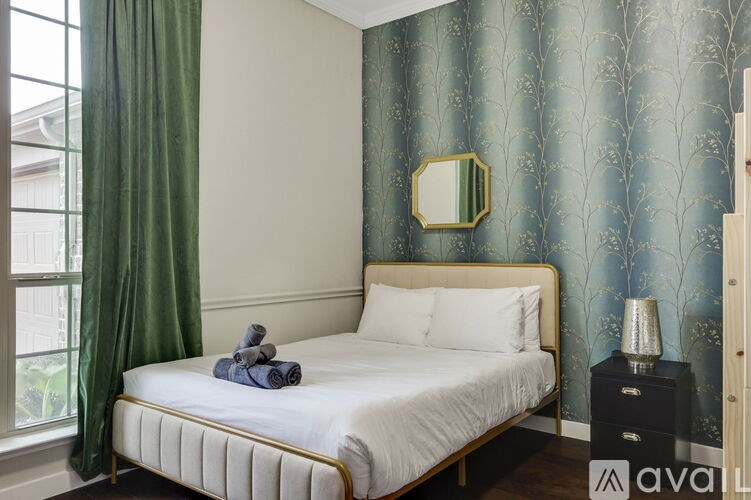 A bedroom with a bed, nightstand, and a window with green curtains.