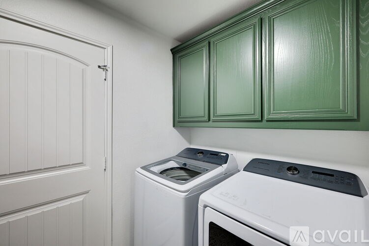 A white dishwasher and dryer are in a kitchen with green cabinets.