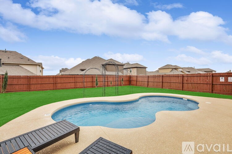 A pool surrounded by a wooden fence with a bench in the foreground.