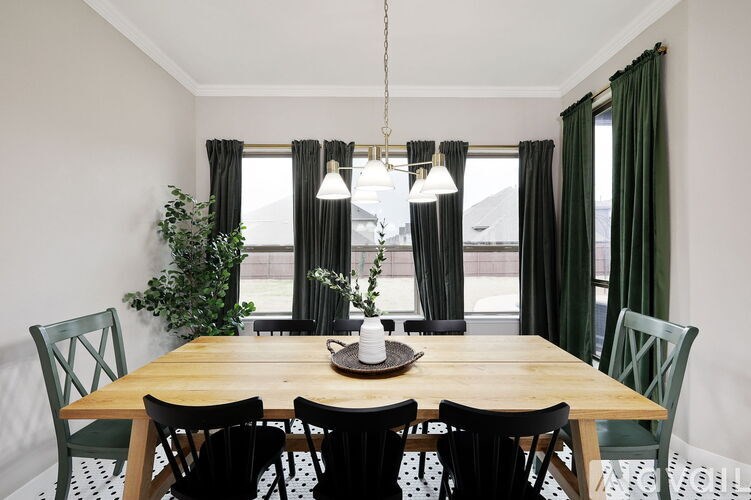 A dining room with a wooden table and green chairs.