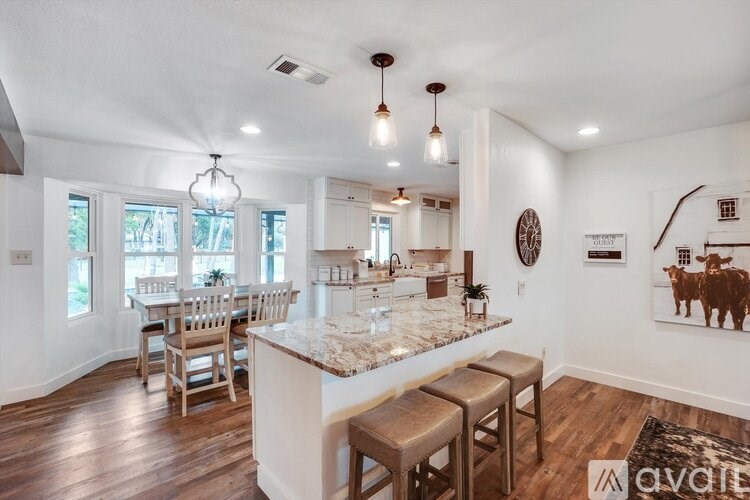 A kitchen with a marble countertop and wooden floors.