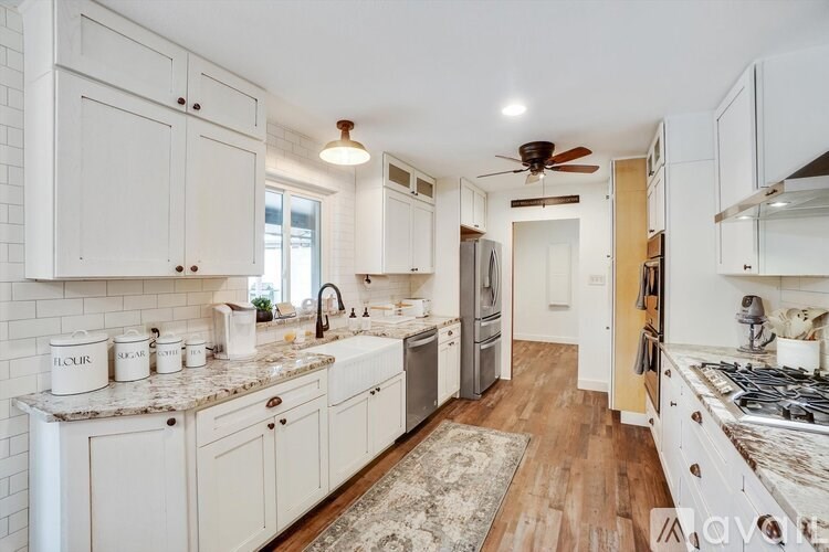A kitchen with white cabinets and a wooden floor.