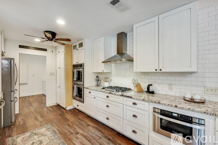 A kitchen with white cabinets and a wooden floor.