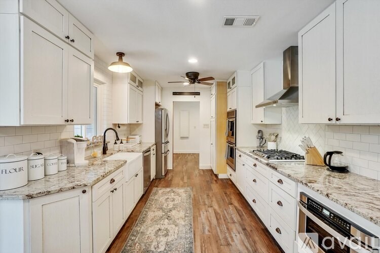 A kitchen with white cabinets and a marble countertop.